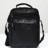 bolso negro para hombre o mujer de piel con cuatro cremalleras en la mesa