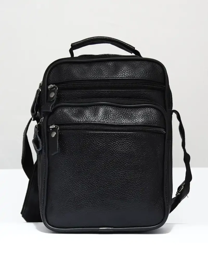 bolso negro para hombre o mujer de piel con cuatro cremalleras en la mesa