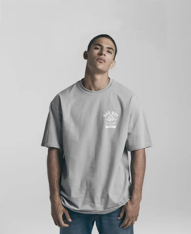 chico modelo en camiseta gris claro oversize con diseno de color blanco, bad boy, edicion limitada, vista frontal