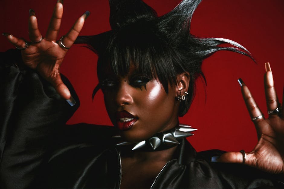Striking portrait of a woman with punk hairstyle and jewelry on red background.