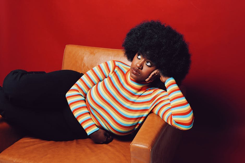 Tendencias Primavera-Verano 2025 Portrait of a fashionable African American woman in a colorful sweater, lounging stylishly.