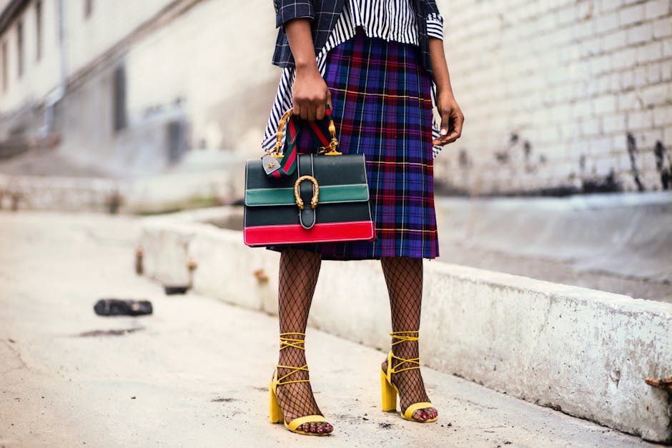 Qué es un Outfit? Fashion-forward outfit with plaid skirt and colorful handbag in urban setting.